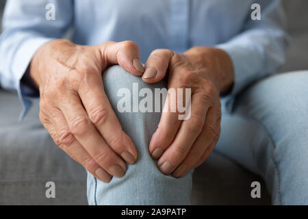 Vecchia donna toccante sensazione di ginocchio dolore affetti da osteoartrosi, primo piano Foto Stock