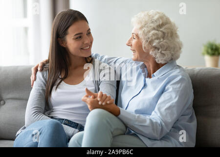 Vecchia nonna e giovane adulto nipote parlando l'incollaggio sul divano Foto Stock
