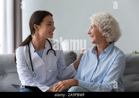 Felice femmina giovane infermiere fornire servizio medico il supporto vecchia nonna Foto Stock