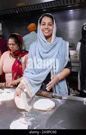 Un attraente donna Sikh sorrisi mentre rendendo roti pane in un Langar, gratuitamente una cucina in comune. Nel Sud di Richmond Foto Stock