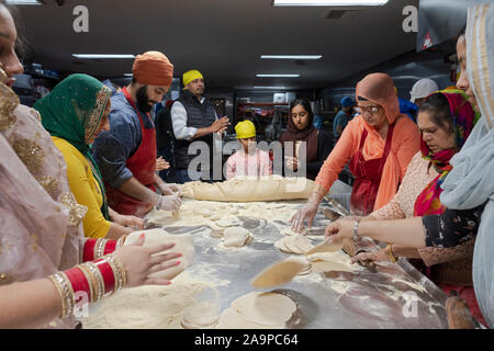 La religione sikh di uomini e donne di tutte le età preparare roti pane in un Langar, gratuitamente una cucina in comune. In South Richmond Hill, Queens, a New York City. Foto Stock