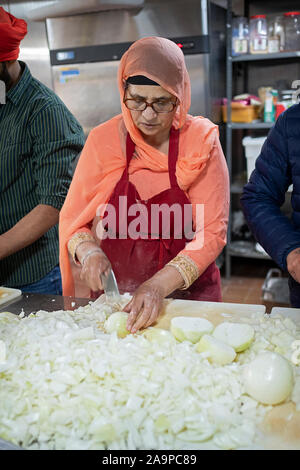 Una donna Sikh volontario tagliare cipolle in un Langar, gratuitamente una cucina in comune. In South Richmond Hill, Queens, a New York City. Foto Stock