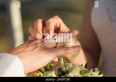 Le mani della sposa mettere un anello per lo sposo. Giorno di nozze. Foto Stock