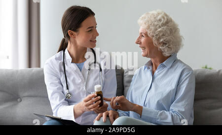 Donna sorridente medico di prescrivere medicine a felice senior nonna paziente Foto Stock