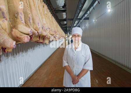 Bilarus, la città di Gomil, 26 aprile 2019.9. La fabbrica di carne. Macello lavoratore sullo sfondo di carcasse di carne di maiale. Industria della carne. Slaughterhou Foto Stock