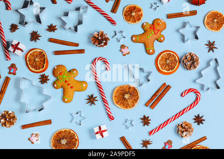 Gastronomia natalizia gingerbread cookie caramella della canna da zucchero cannella forma dello stampo anice fetta di arancia e di doni su sfondo blu Foto Stock