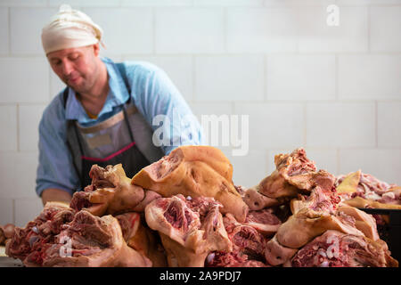 Bilarus, la città di Gomil, 26 aprile 2019. La fabbrica di carne. Macello. Lavoratore nel negozio di carne al lavoro. Macelleria maschio tagli carcasse di maiale Foto Stock