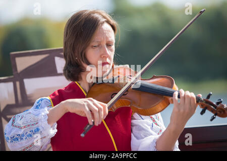 La Bielorussia, la città di Gomil, 14 settembre 2019. Città delle vacanze. Donna slava musicista di strada. Ucraino o ragazza bielorussa in una camicia ricamata gioca Foto Stock