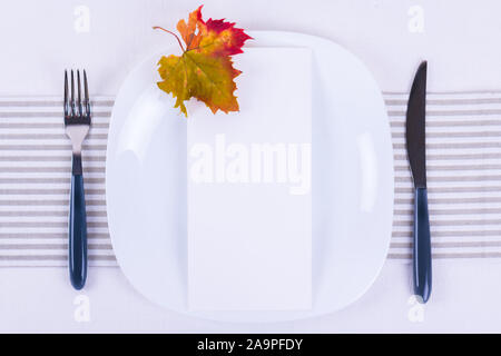 Whiete scheda vuota mock up invito o menu in bianco la piastra di porcellana con caduta di festa messa in tavola con colorate Foglie di autunno. Ristorante minima Foto Stock