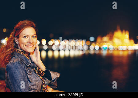 Felice redhead giovane donna urbano ritratto notturno sul ponte, Budapest, Ungheria Foto Stock