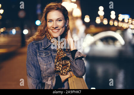 Felice giovane donna sorriso toothy sul ponte Margherita di notte, Budapest, Ungheria Foto Stock