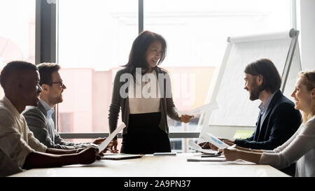 Di mezza età femmina coreano team leader per discutere di un progetto con i compagni di squadra. Foto Stock