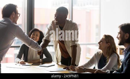Fiducioso team leader stringono le mani con sorridente americano africano dipendente. Foto Stock