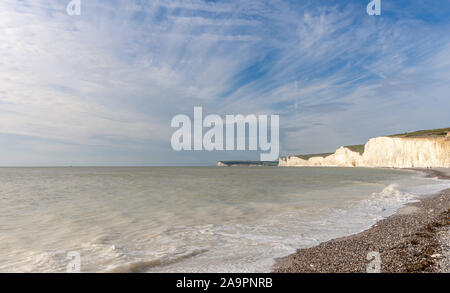 Chalk scogliere di Beachy Head tendere all'orizzonte con un basso sun evidenziando le superfici bianche. Un cielo blu è sovraccarico. Foto Stock