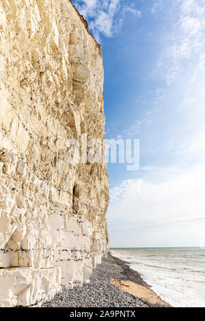 Un close-up del famoso chalk scogliere di Beachy Head. Giro delle onde sulla spiaggia sottostante e un cielo blu è sovraccarico. Foto Stock