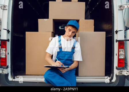 Deliveryman in uniforme, pacchi in auto, cargo Foto Stock
