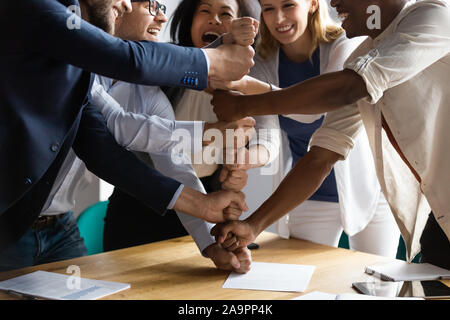 Overjoyed giovani vecchi razza mista di squadra rendendo piramide dei pugni. Foto Stock
