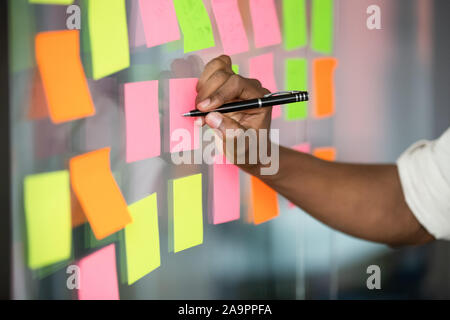 Close up americano africano manager note di scrittura sulla scheda kanban. Foto Stock