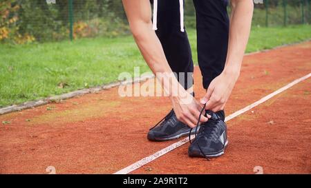 Montare giovane uomo occupare scarpe, ottenere pronto per Morning jog sulla gara di corsa via Foto Stock