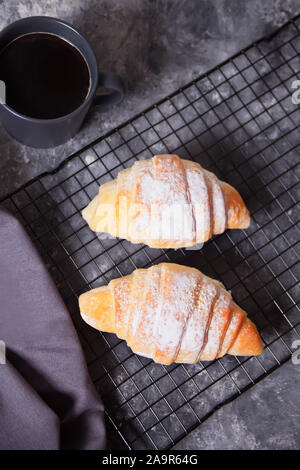 Cornetti freschi panini sulla griglia da forno e la tazza di caffè nelle vicinanze Foto Stock