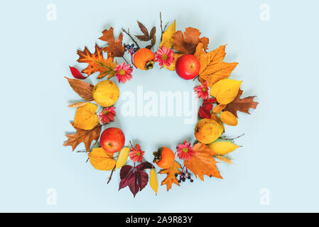 Una ghirlanda di vari colori d'autunno frutti e foglie su fondo azzurro. Foto Stock