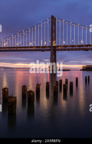 Vista di Oakland Bay Bridge nelle prime ore del mattino dal molo vicino a Rincon Park di San Francisco, California Foto Stock