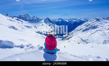 Snowboard ragazza seduta sulla neve in Mölltaler Gletscher, Austria, godendo della vista. Un sacco di neve in montagna. Interminabile catena delle Alpi. Inverno wo Foto Stock