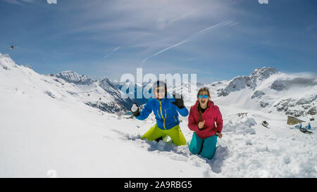 Un paio di sci outfits giocando nella polvere di neve. Essi stanno lanciando palle di neve e ridere a voce alta, tempo di gioco. Gamme infinite di neve tappata mou Foto Stock