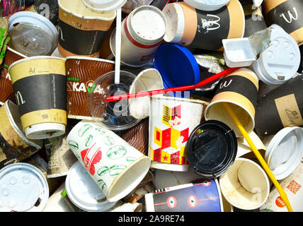 14.05.2019, Minsk, Bielorussia: scartato tazze da caffè e fast food packaging nella foresta sul terreno. Le persone a sinistra dietro il cestino. Il concetto di inquinamento Foto Stock