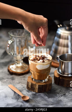 Il caffè cocktail. Snella donna decorazione a mano caffè con cioccolato rade in breve vetro su sfondo scuro fuoco selettivo Foto Stock