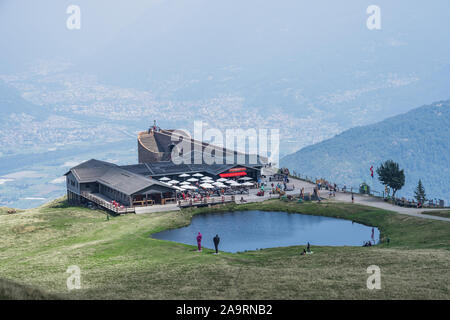 Ticino, Svizzera - 5 Agosto 2019: ristorante Alpe Foppa, La Cappella e il lago sulla sommità del Monte Tamaro con Borgo Ticino Foto Stock