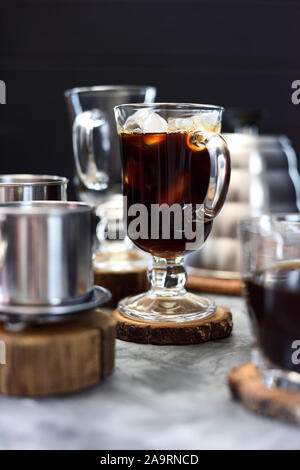 Rendendo il vietnamita nero ghiaccio antigoccia caffè nella tazza irlandese su sfondo nero il fuoco selettivo Foto Stock