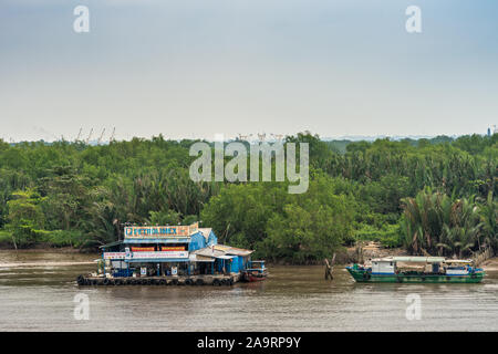 Ho Chi Minh City Vietnam - Marzo 12, 2019: Petrolimex stazione di gas per imbarcazioni da fiume con banner colorati sul pontone su Canzone Sai Gon river con verde fo Foto Stock