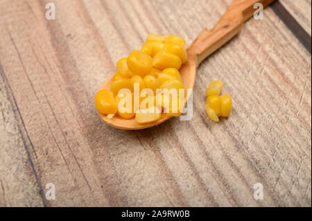 Dolci chicchi di mais in un cucchiaio di legno su una tavola di legno. Dieta Fitness. Dieta sana. Per una dolcezza. Close up Foto Stock