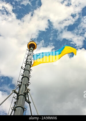 Bandiera dell'Ucraina appesi al flagstaff e sventolare nel vento, installato sul Municipio di Lviv, Ucraina Foto Stock