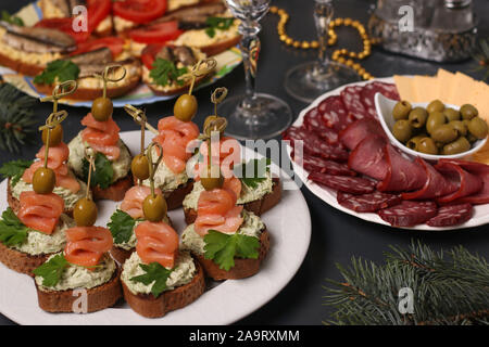 Antipasto su una tavola festiva - crostini con salmone, panini con lo spratto e fette di formaggio e salsicce Foto Stock