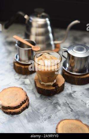 Facendo gocciolare ghiacciata caffè con il latte di cocco in stile vietnamita su sfondo scuro in verticale Foto Stock