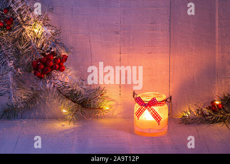 Lanterna di natale e rami di abete rosso con decorazioni di Natale sul rustico sfondo di legno al crepuscolo . Tonica immagine. Foto Stock