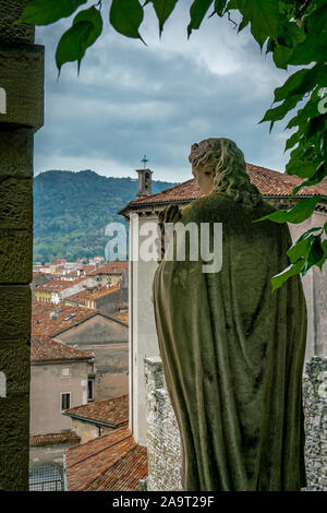 Affacciato sulla città italiana Vittorio Veneto dalla sommità della Scalinata di Santa Augusta con la statua in primo piano incorniciato in un arco di foglie Foto Stock