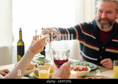 Uomo maturo e sua figlia il tintinnio con bicchieri di vino oltre snack sulla tabella Foto Stock