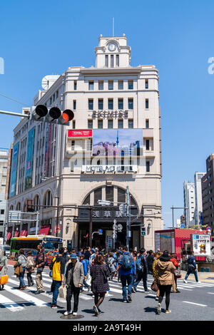 Tokyo, stazione di Asakusa edificio esterno condiviso con il Ministero Matsuya store, contro il cielo blu. Primo piano, persone con attraversamento pedonale. Foto Stock