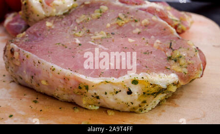 La carne di maiale o di manzo bistecche, decapato in spezie per friggere, giacciono sulla scheda di cucina. Close-up. Foto Stock