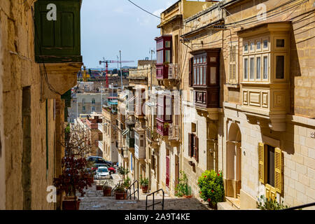 Strada stretta nella Cospicua (Bormla), Malta, con scale e balconi chiusi Foto Stock