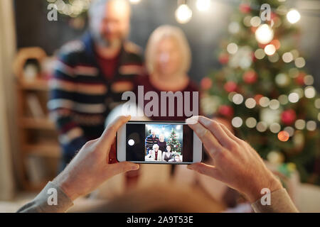 Le mani di uomo con smartphone durante l assunzione di foto della grande famiglia rilassata Foto Stock