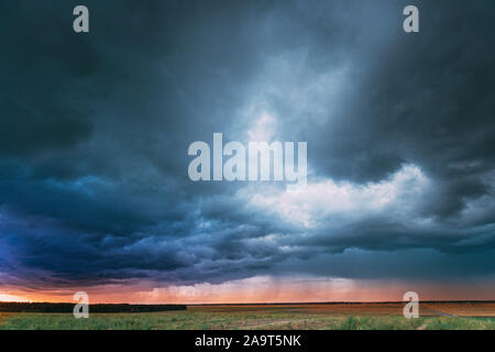 Estate piovosa sera al tramonto sopra Campo rurale paesaggio. Scenic drammatico Sky con pioggia nuvole. Agricola e previsioni meteo Concept Foto Stock