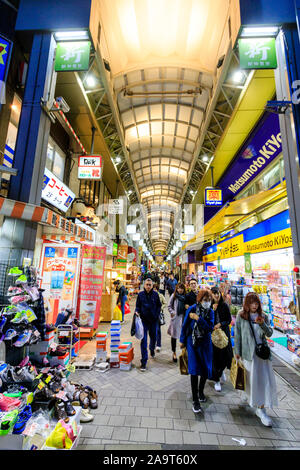 Tokyo, Asakusa. Oggetto shopping arcade off Nakamise Dori, street al Tempio di Asakusa. Vista lungo interno con gli acquirenti a piedi verso il visualizzatore. Notte. Foto Stock