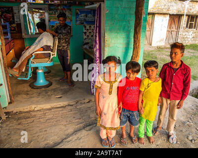 Indian ragazzi e una ragazza di fronte ad un taglio di capelli saloon al villaggio Pawalgarh, Uttarakhand, India Foto Stock