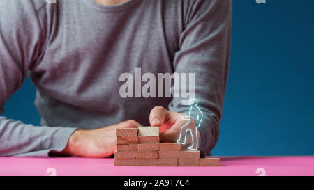 L'uomo facendo passi di picchetti in legno per un incandescente forma di un uomo che cammina verso l'alto in una immagine concettuale. Foto Stock