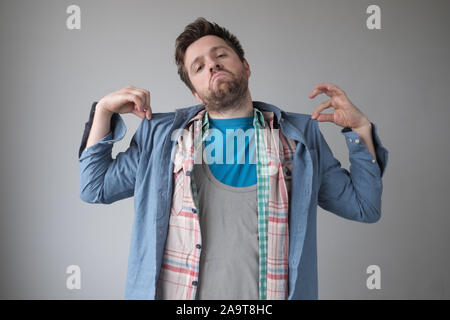 Fumetto effeminato uomo che indossa diversi shirt. Ho messo su tutti i miei abiti migliori. Studio shot Foto Stock