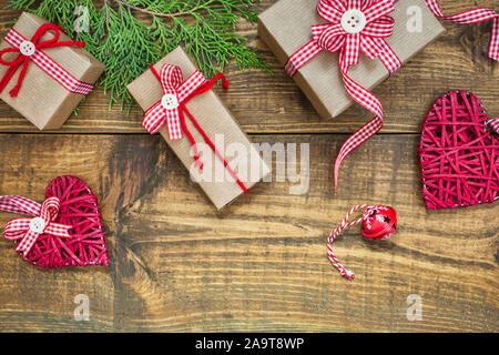 Composizione di Natale fatti a mano con confezioni regalo avvolto in carta craft, rami e decorazioni su tavola in legno rustico. Natale o Capodanno Saluto Foto Stock